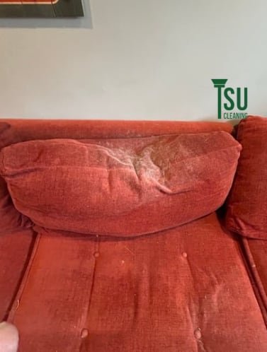 Rust-colored fabric sofa before cleaning, with the pile matted and dulled
