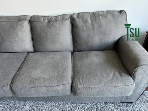 The same grey sofa after cleaning, with the stain removed and the cushions even in tone